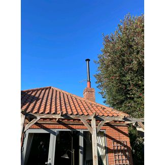 Black twin wall flue being used to stop down draft by raising the height of the chimney