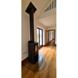 Di Lusso Euro R5 woodburner with a black twin wall flue and semi circle clear glass hearth